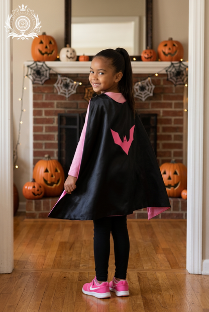Girl wearing black-and-pink cape with Halloween backdrop